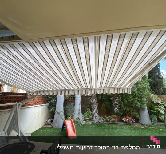 סוכך בד פסים לבן וחום בחצר